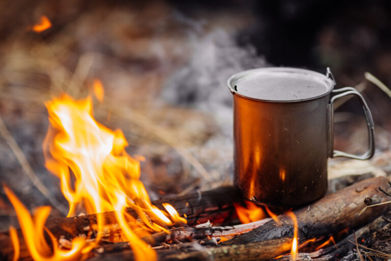 Titanbecher auf Holz auf Waldhintergrund